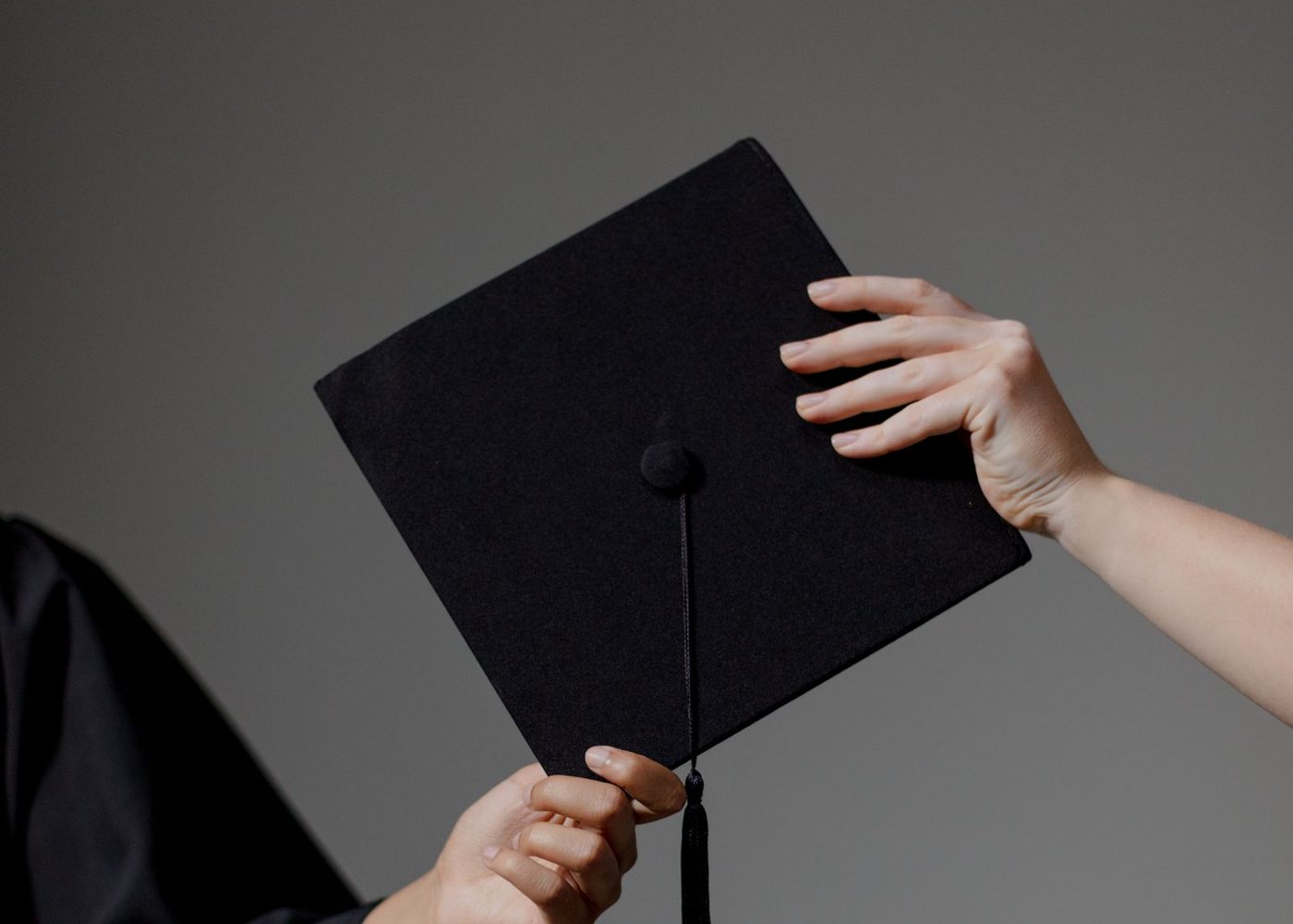 Hands holding a graduation cap