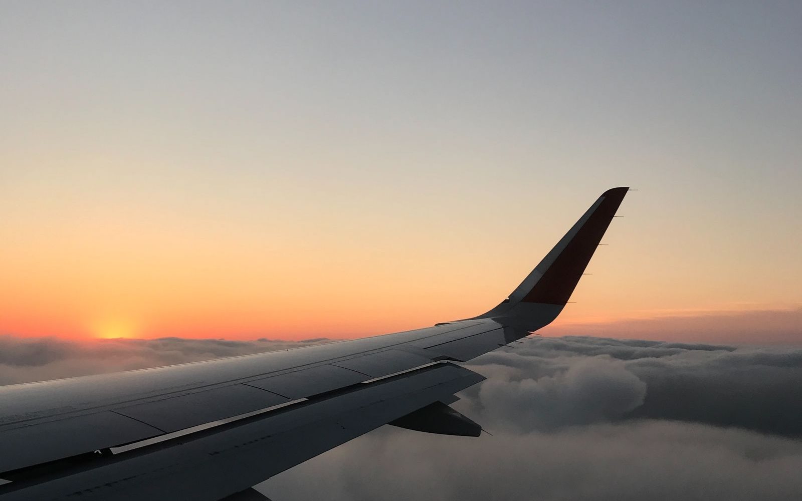 Aircraft wing above the clouds at sunset